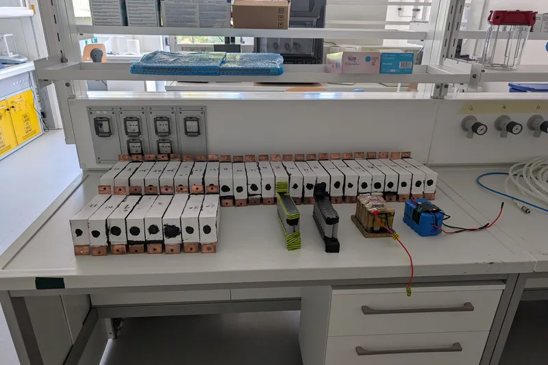 A long row of finished white modules with copper terminals on a laboratory bench.