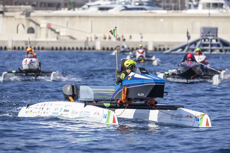 The ALEA electric catamaran racing on open water at Monaco, with other boats behind.