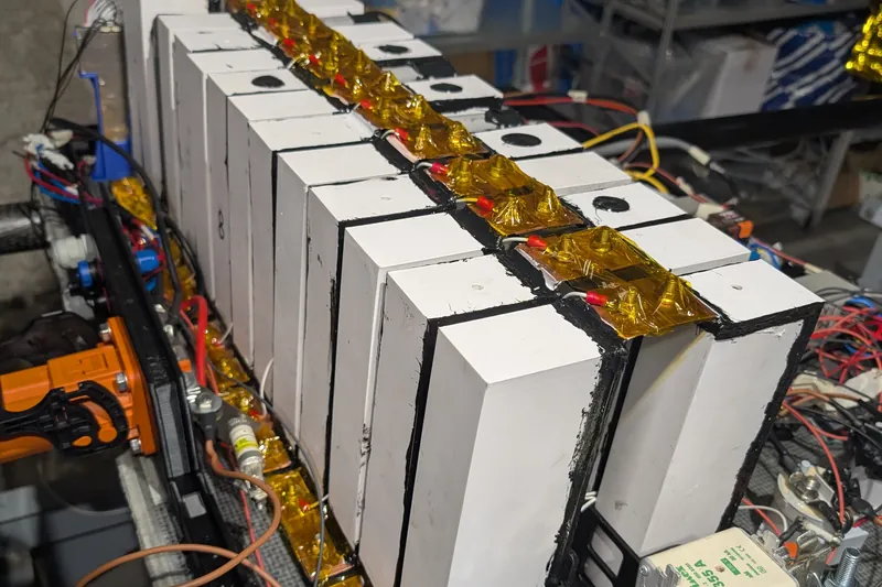 The assembled battery pack: a row of white modules with copper busbars and wiring along the top.