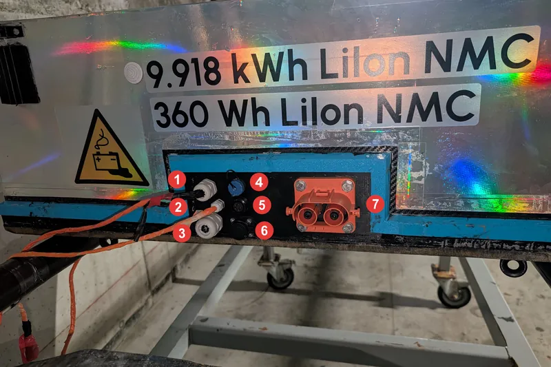 A metallic battery enclosure labelled 9.918 kWh Li-ion NMC with numbered connectors and an orange power plug.